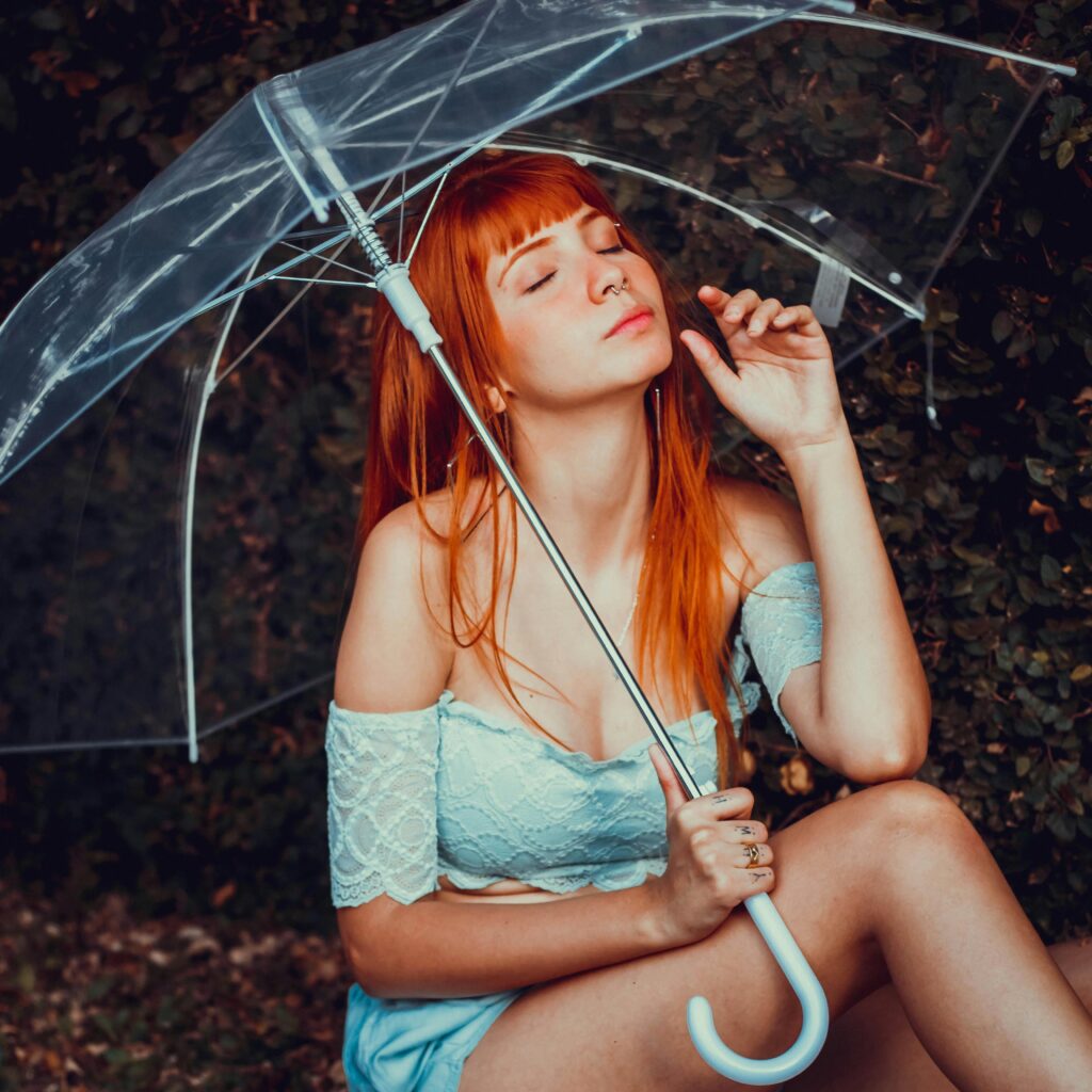 A pretty woman in a blue skirt holding an umbrella