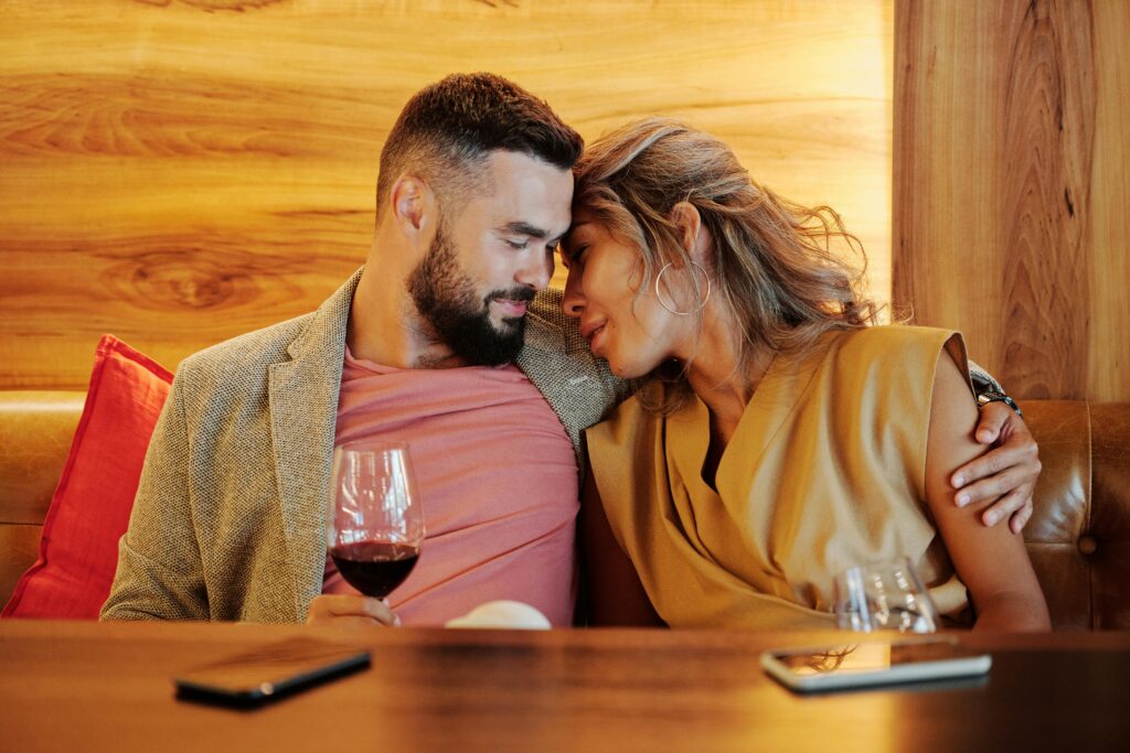 A man and woman lovingly embracing in a restaurant with wood panelled walls and table.