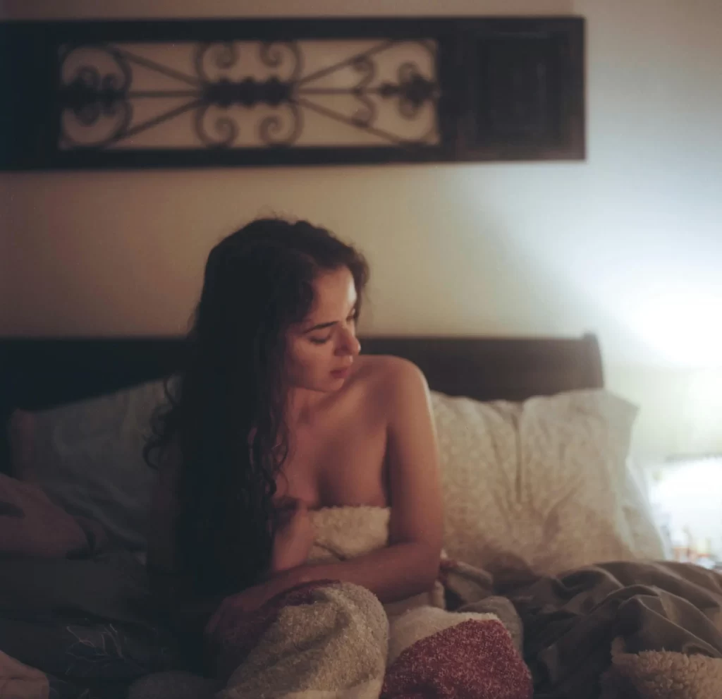 Beautiful brunette woman sitting in her bed wrapped in her blanket