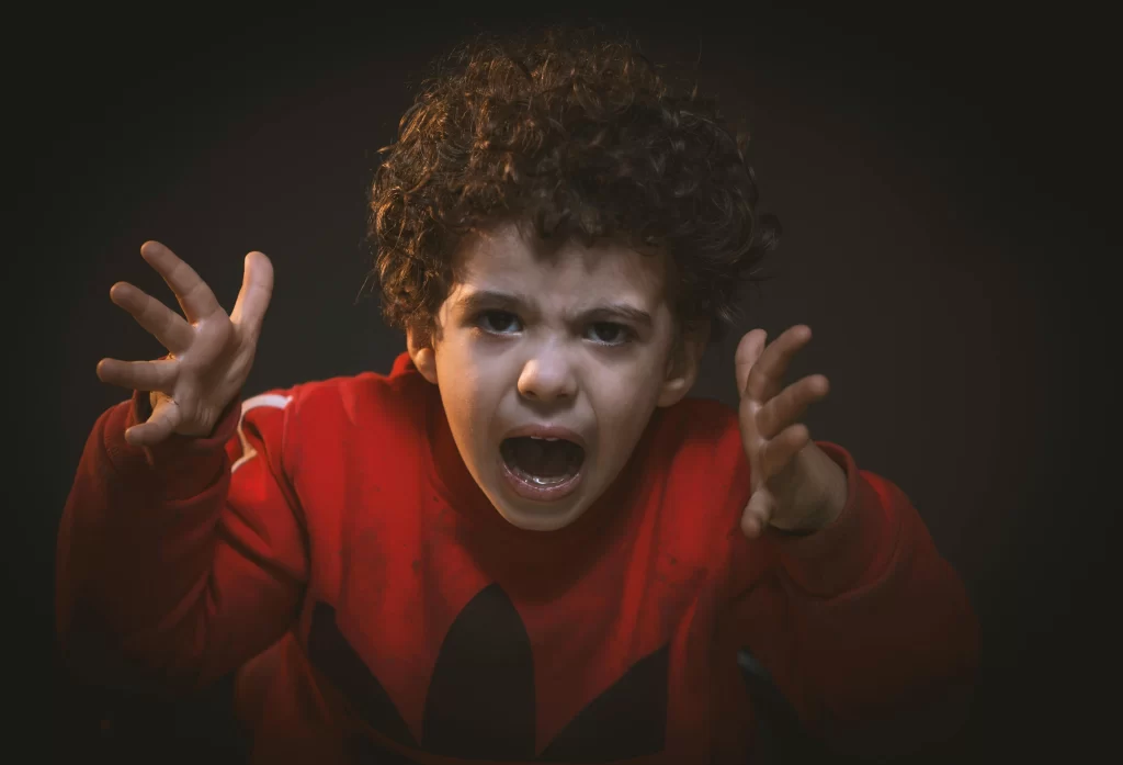 A child holding up his hands and yelling in anger