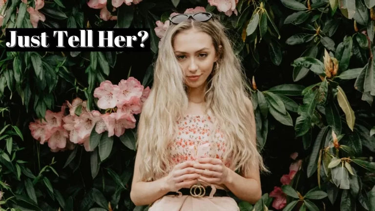 Blonde girl standing in front of bushes with flowers