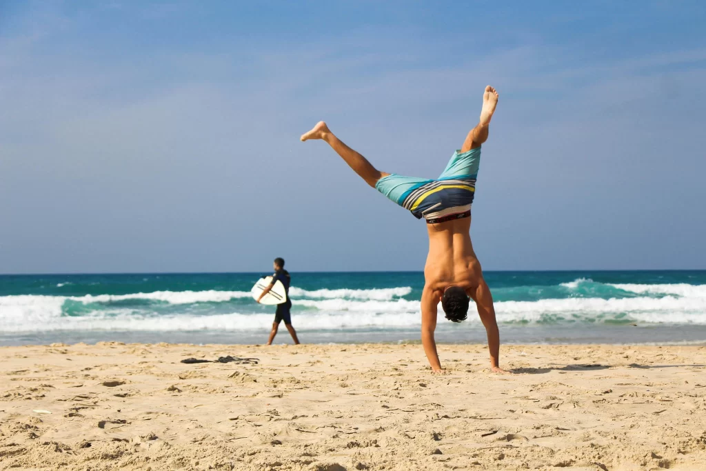 Man doing a cartwheel shirtless at the beach
