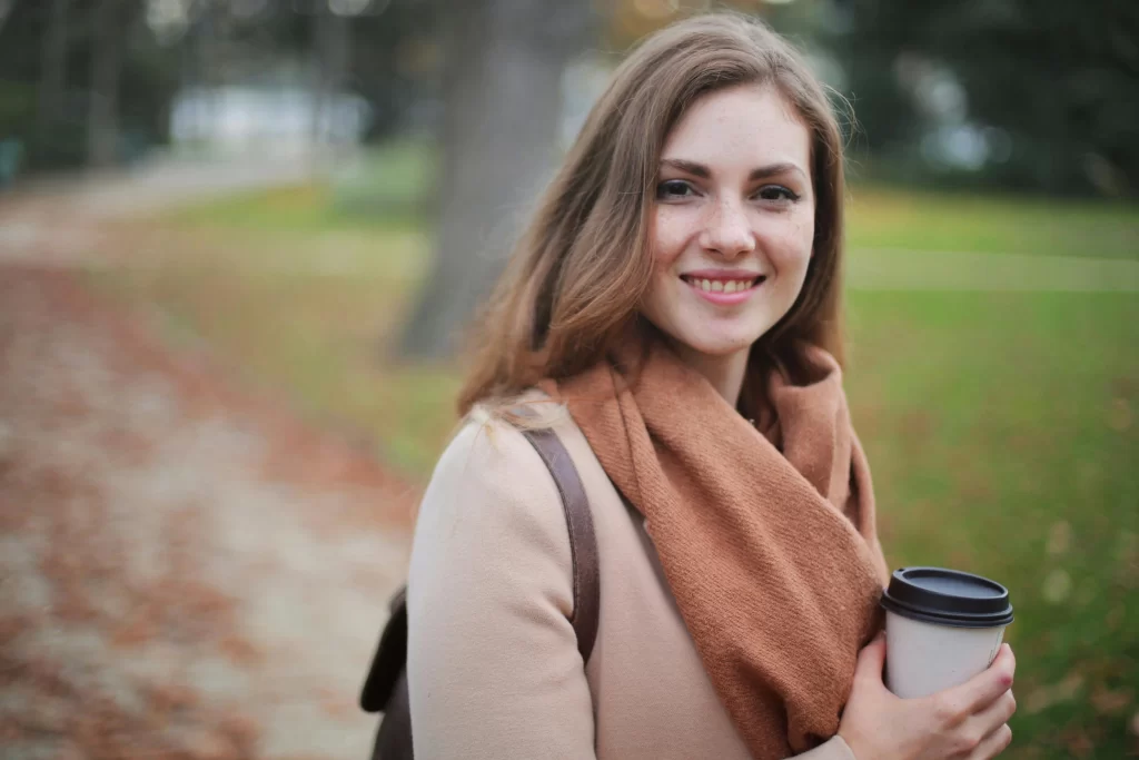 Pretty woman in a brown scarf in a park smiling 