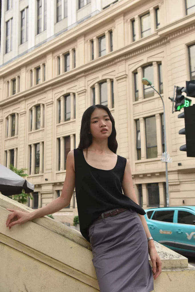 At attractive asian woman in a black blouse leaning on a hand railing on a street side