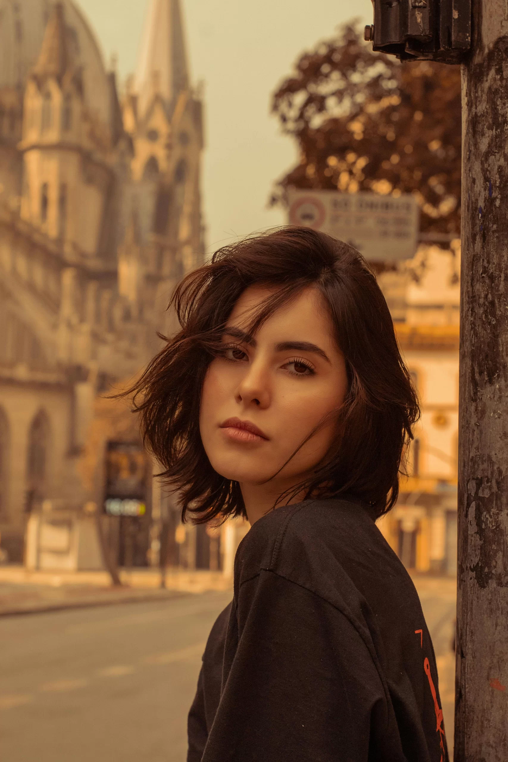 An attractive short haired brunette woman smiling at the camera somewhere in Europe