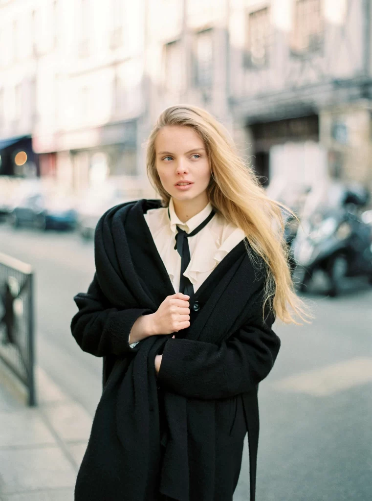 A pretty blonde woman in a black coat on the streets in fall